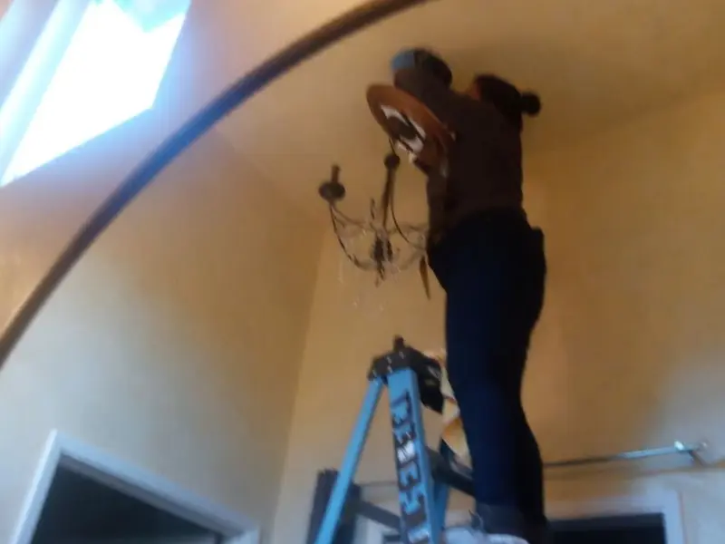 Electrician installing a chandelier in a Clarence residence